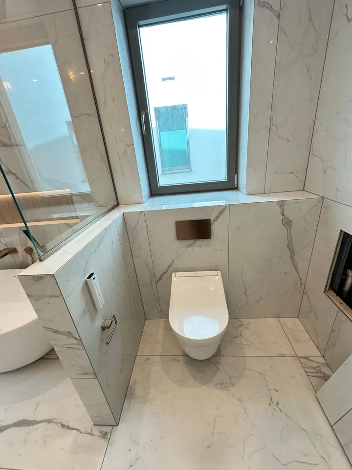Light stone-look bathroom with bath and sanitaryware